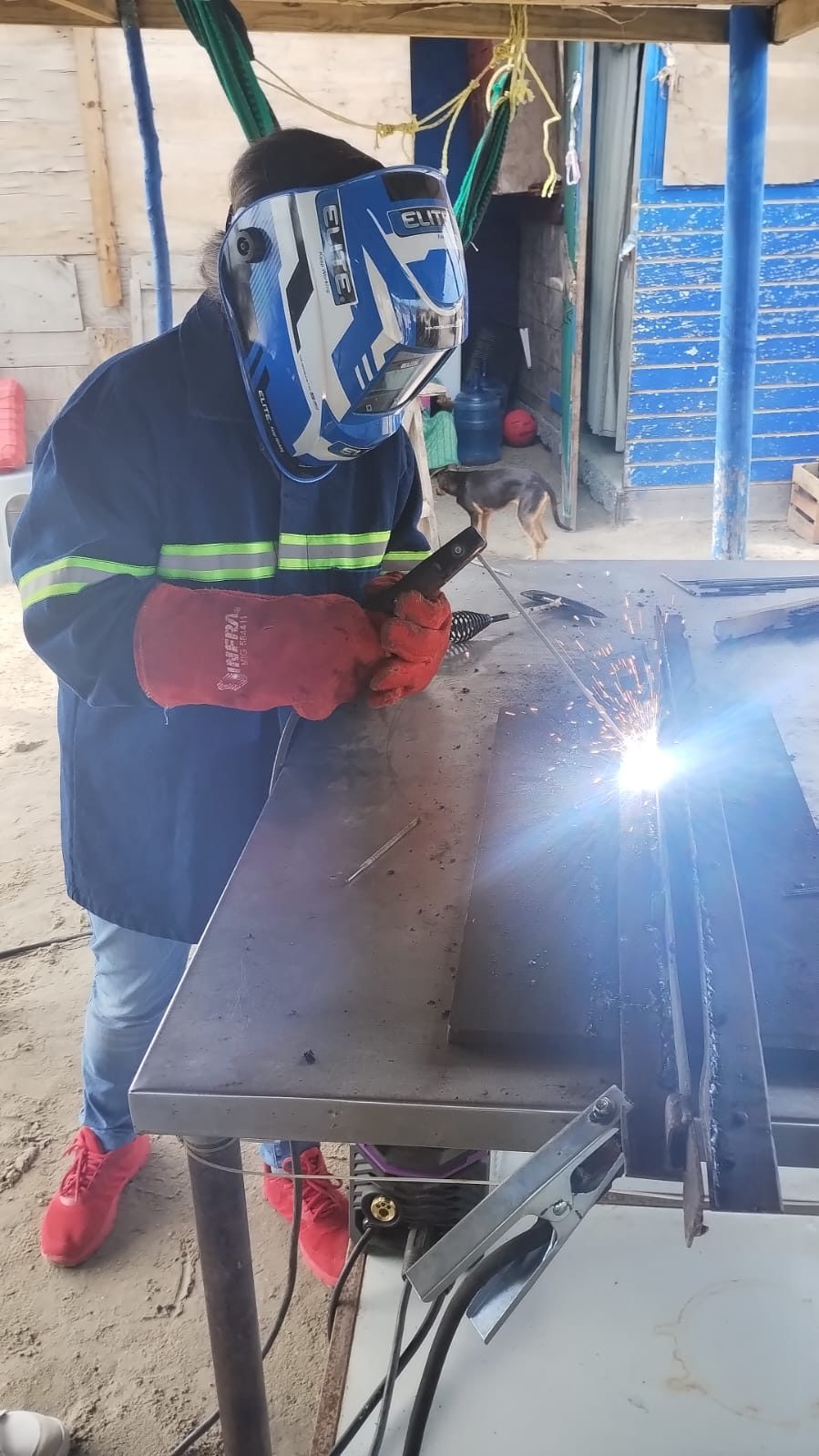 Participante practicando soldadura eléctrica en superficie plana